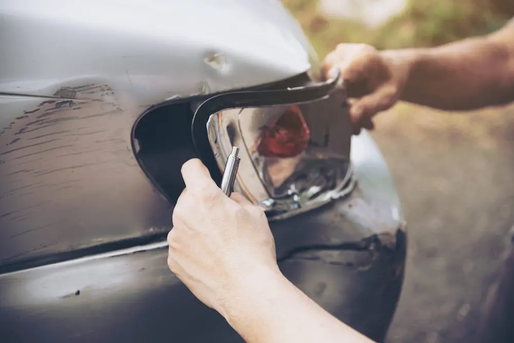 Home | Non-Fault Accident Claim & Vehicle Recovery London Mechanic inspecting a damaged headlight during vehicle assessment managed by SSS Claims accident management UK.