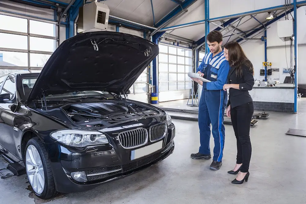 Home | Non-Fault Accident Claim & Vehicle Recovery London Mechanic and customer inspecting a damaged car inside an approved vehicle repair garage managed by SSS Claims accident management UK.